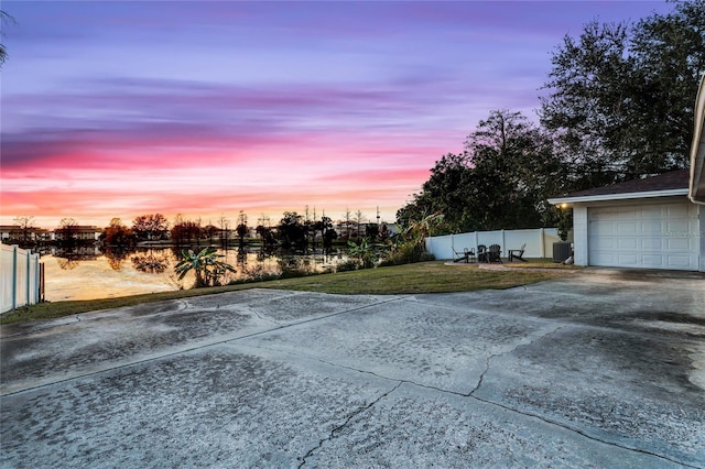 exterior space with a garage, central air condition unit, and a water view