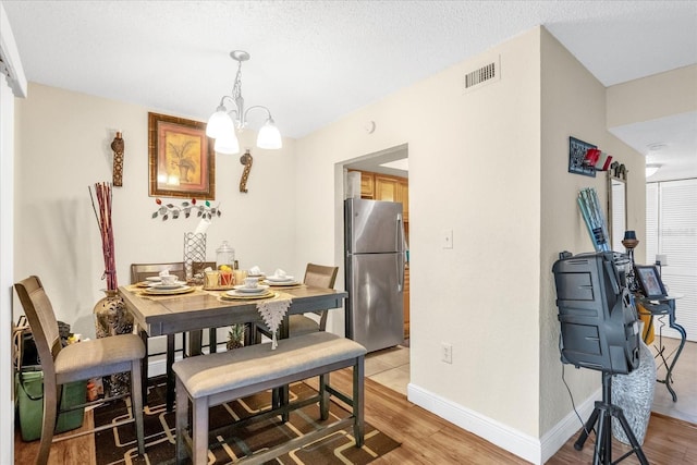 dining space with a notable chandelier, hardwood / wood-style flooring, and a textured ceiling