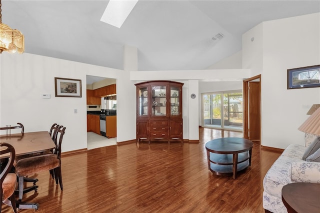 living room featuring dark hardwood / wood-style flooring, a skylight, and high vaulted ceiling