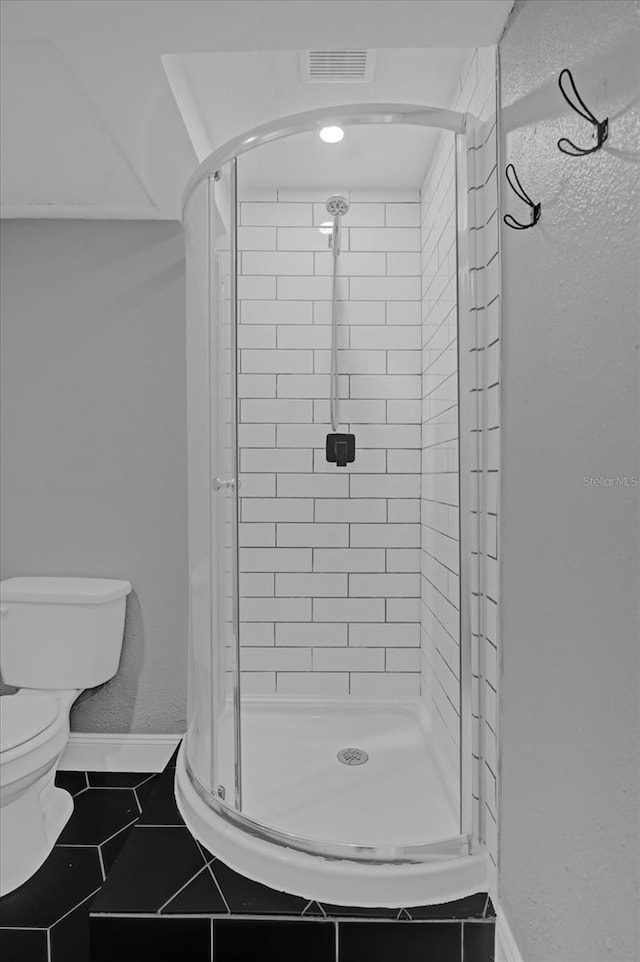 bathroom with toilet, tile patterned floors, and a shower with shower door