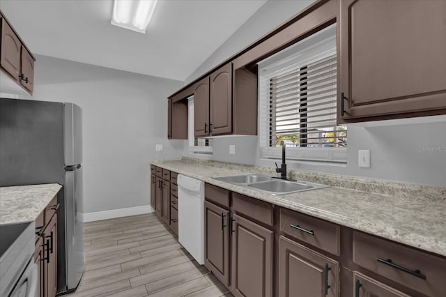 kitchen featuring dark brown cabinetry, sink, stainless steel fridge, and white dishwasher