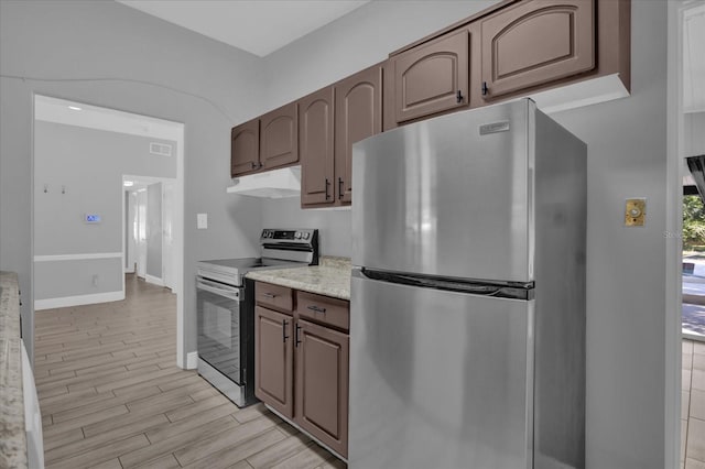 kitchen with appliances with stainless steel finishes, dark brown cabinets, and light wood-type flooring