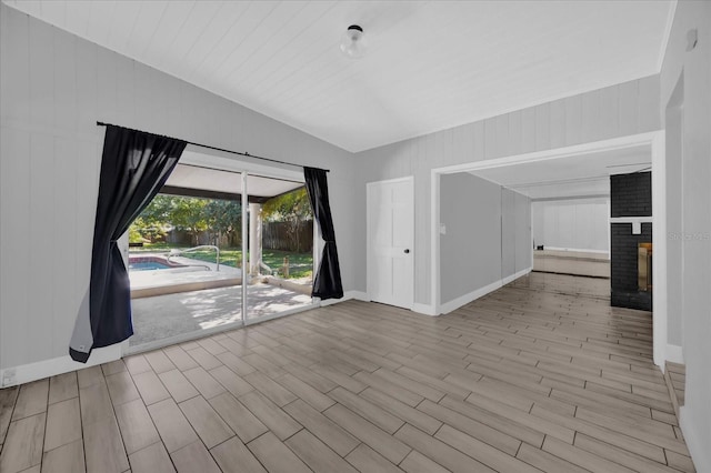 interior space featuring a brick fireplace, vaulted ceiling, and light wood-type flooring