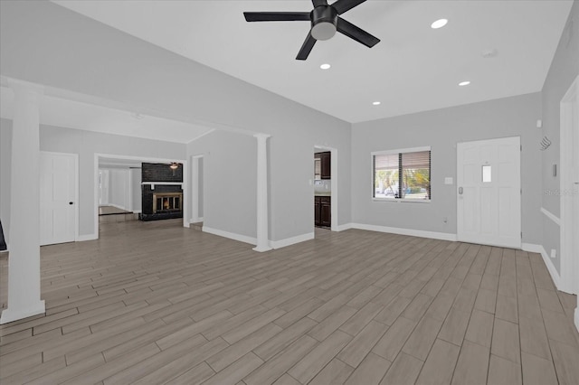 unfurnished living room featuring ceiling fan, a fireplace, and light wood-type flooring