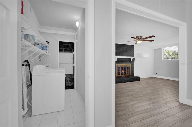 washroom featuring a fireplace, washing machine and dryer, ceiling fan, and light wood-type flooring