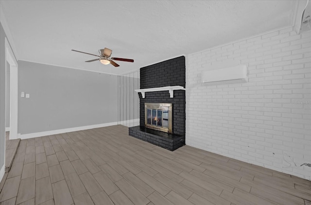 unfurnished living room with ceiling fan, brick wall, a brick fireplace, and a wall unit AC