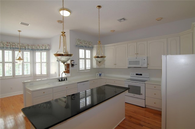 kitchen featuring visible vents, white cabinetry, a sink, light wood-type flooring, and white appliances