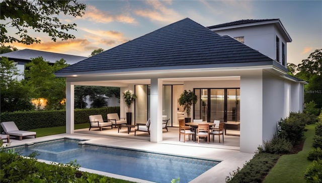 back house at dusk with an outdoor structure, an outdoor hangout area, and a patio area