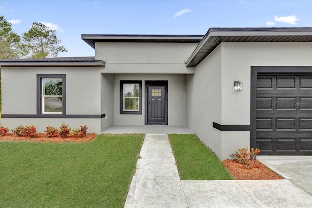 view of exterior entry featuring a garage and a lawn