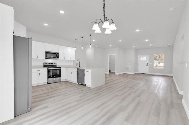 kitchen with decorative light fixtures, white cabinetry, sink, kitchen peninsula, and stainless steel appliances