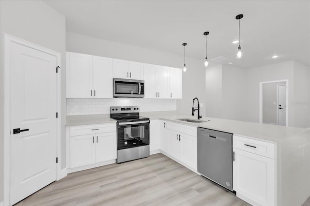 kitchen with pendant lighting, sink, white cabinetry, stainless steel appliances, and kitchen peninsula