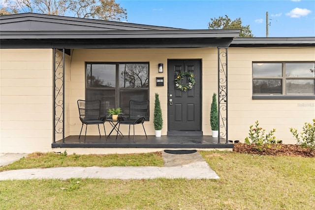 entrance to property featuring a porch and a lawn