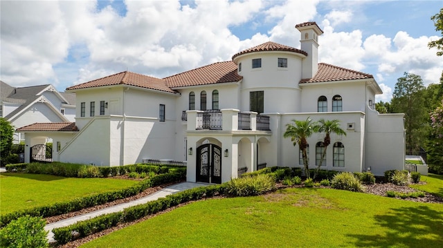 mediterranean / spanish-style house featuring a front yard and a balcony