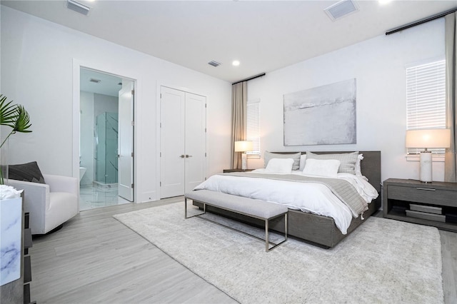 bedroom featuring ensuite bathroom and light wood-type flooring