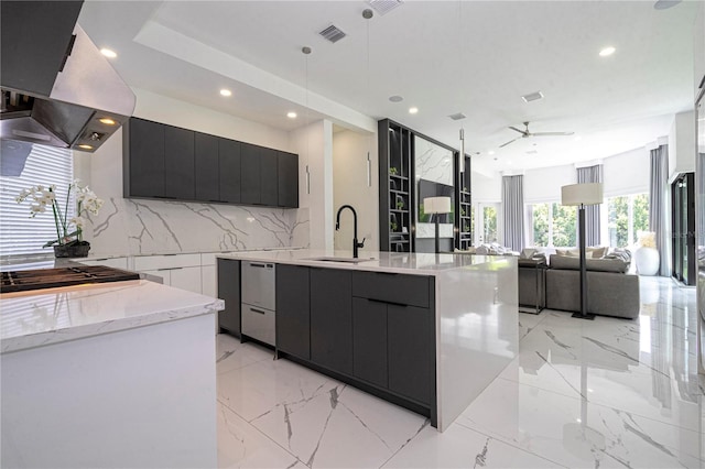 kitchen with sink, decorative backsplash, hanging light fixtures, island exhaust hood, and a center island with sink