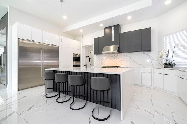 kitchen with pendant lighting, backsplash, stainless steel appliances, and an island with sink