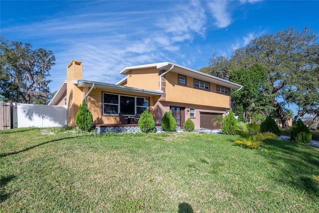 back of property with a garage and a yard