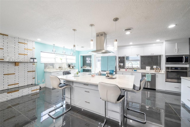 5006 Monet Ave, Belle Isle, FL 32812 - kitchen featuring white cabinets, backsplash, hanging light fixtures, island exhaust hood, and stainless steel appliances