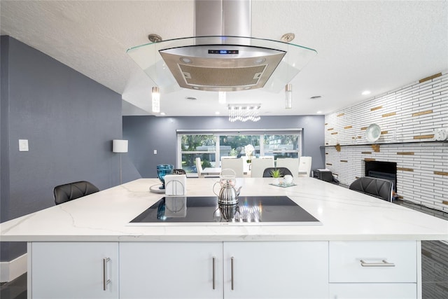 5006 Monet Ave, Belle Isle, FL 32812 - kitchen featuring white cabinetry, light stone counters, a center island, a textured ceiling, and black electric cooktop