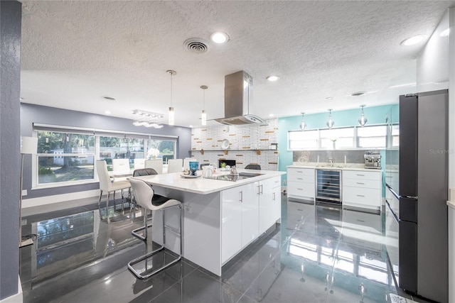 5006 Monet Ave, Belle Isle, FL 32812 - kitchen with backsplash, island range hood, white cabinets, a kitchen island, and beverage cooler