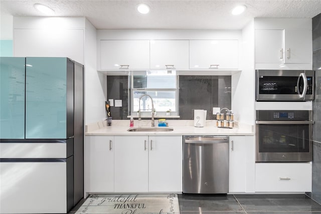 5006 Monet Ave, Belle Isle, FL 32812 - kitchen with sink, stainless steel appliances, a textured ceiling, white cabinets, and dark tile patterned flooring