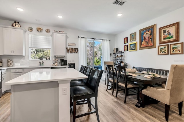 kitchen featuring plenty of natural light, a center island, a kitchen bar, and light hardwood / wood-style flooring