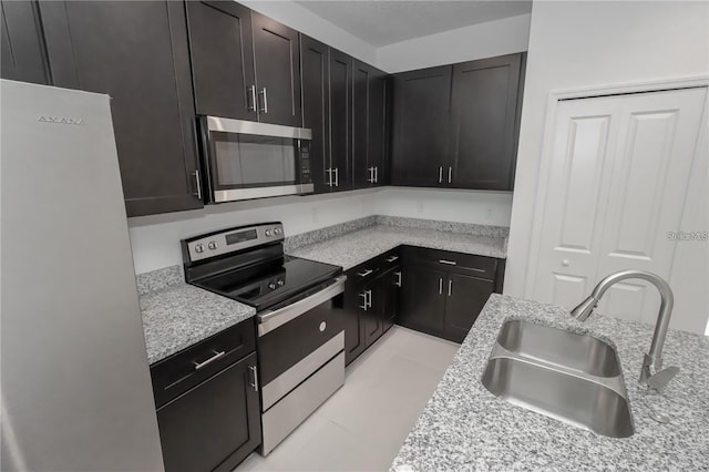 kitchen with light stone counters, stainless steel appliances, and sink