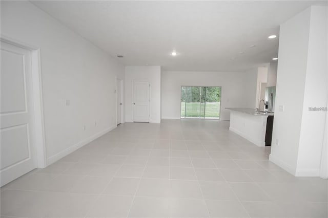 unfurnished living room with sink and light tile patterned floors