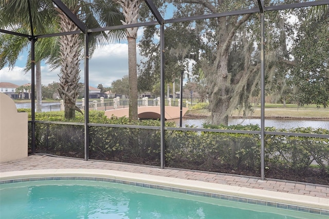 view of pool with a water view and glass enclosure