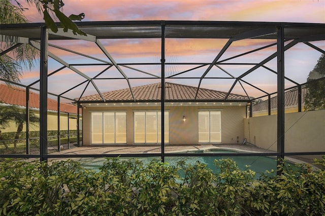 back house at dusk with a lanai and a patio area