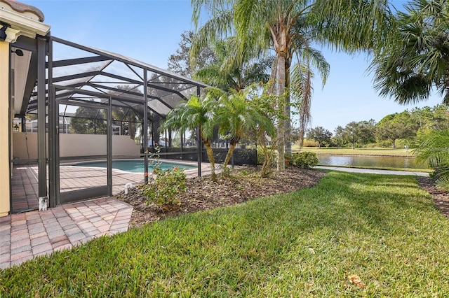 view of yard featuring a water view, glass enclosure, and a patio area