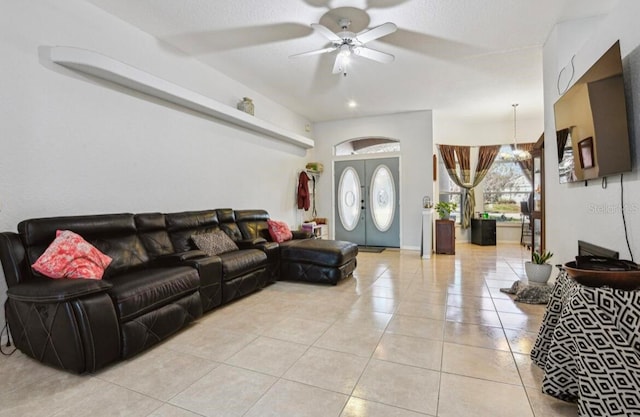 tiled living room with french doors and ceiling fan with notable chandelier