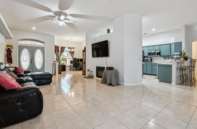 tiled living room with french doors and ceiling fan with notable chandelier