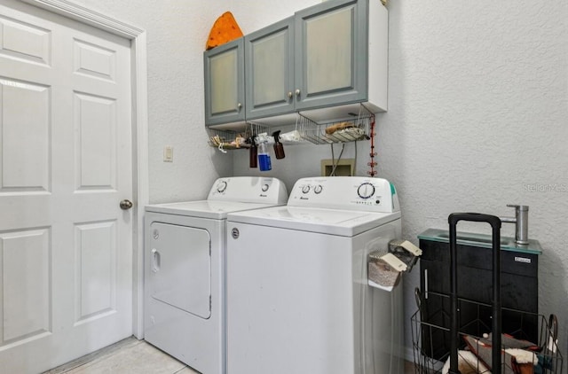 washroom with cabinets, light tile patterned flooring, and washing machine and clothes dryer