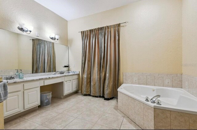 bathroom featuring vanity, tile patterned flooring, a relaxing tiled tub, and a textured ceiling