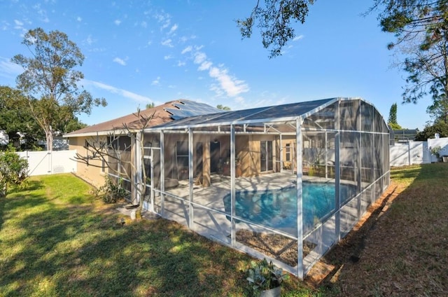 rear view of house with a fenced in pool, a yard, glass enclosure, and solar panels