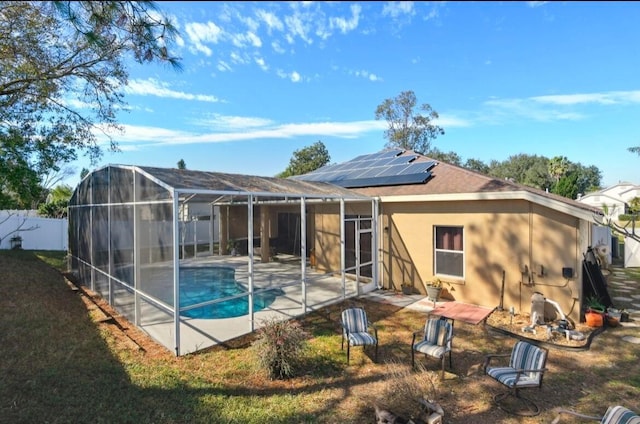 rear view of property featuring a patio, a lanai, a yard, and solar panels