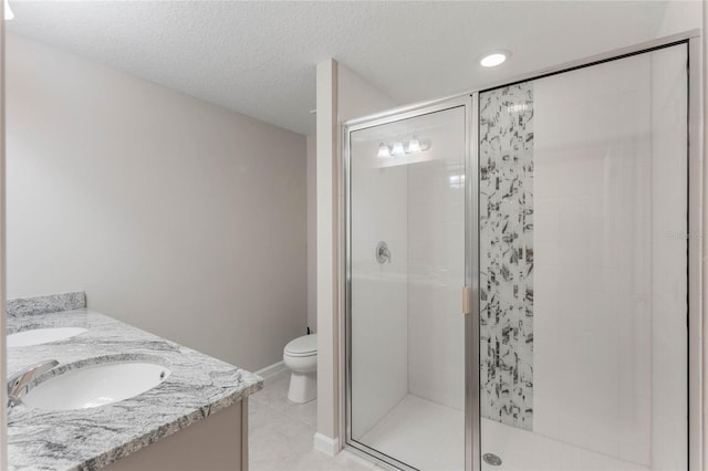 bathroom featuring a shower with door, vanity, a textured ceiling, and toilet