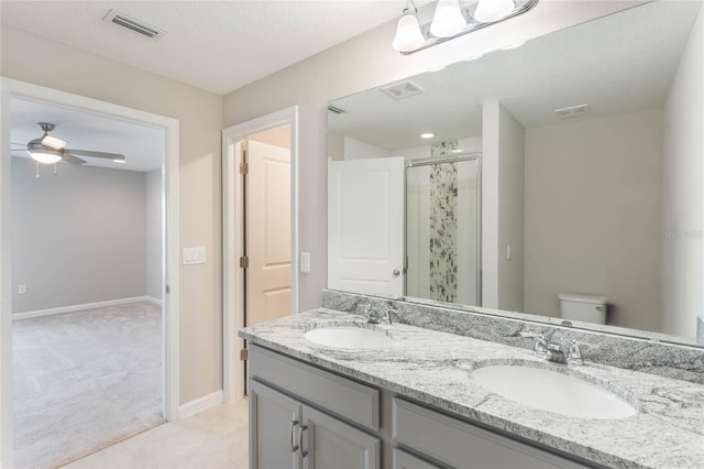 bathroom with vanity, an enclosed shower, ceiling fan, toilet, and a textured ceiling