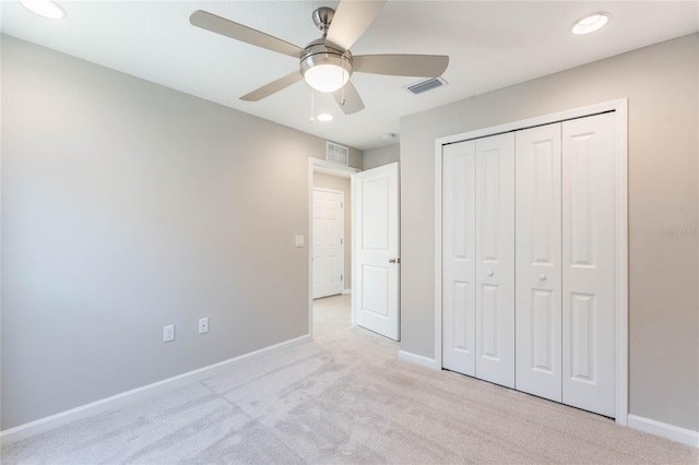 unfurnished bedroom with light colored carpet, ceiling fan, and a closet