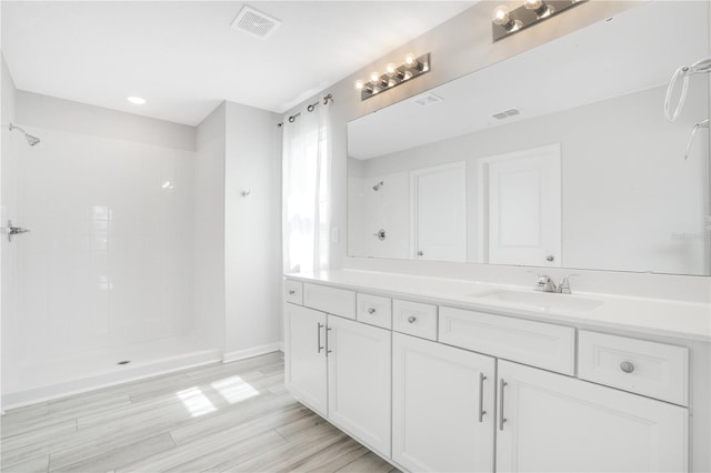 332 Bow Ln, Haines City, FL 33844 - bathroom with tiled shower, visible vents, vanity, and wood finished floors