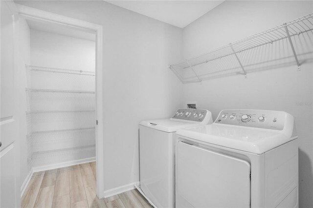 332 Bow Ln, Haines City, FL 33844 - laundry room featuring laundry area, light wood-style flooring, baseboards, and separate washer and dryer