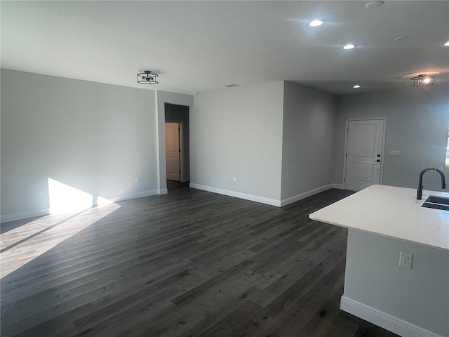 unfurnished living room featuring sink and dark hardwood / wood-style floors