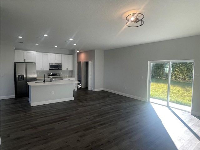 kitchen featuring sink, dark wood-type flooring, white cabinetry, stainless steel appliances, and a center island with sink