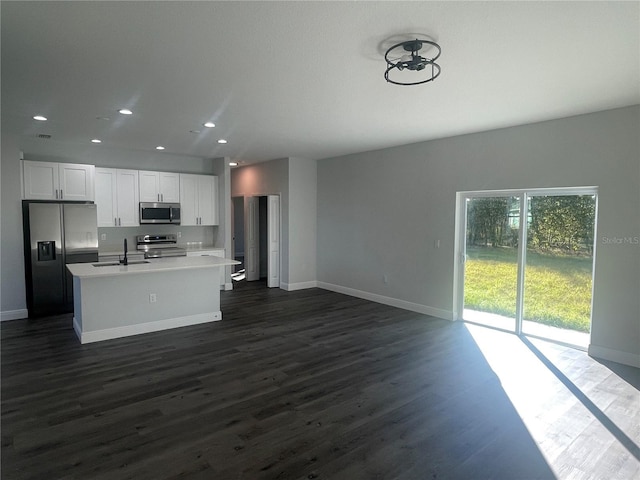 kitchen featuring sink, dark wood-type flooring, appliances with stainless steel finishes, a kitchen island with sink, and white cabinets