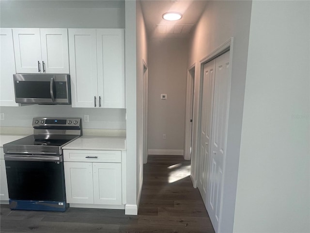 kitchen with appliances with stainless steel finishes, dark hardwood / wood-style flooring, and white cabinets