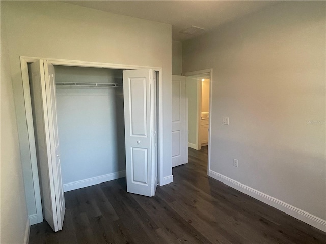 unfurnished bedroom with dark hardwood / wood-style floors and a closet