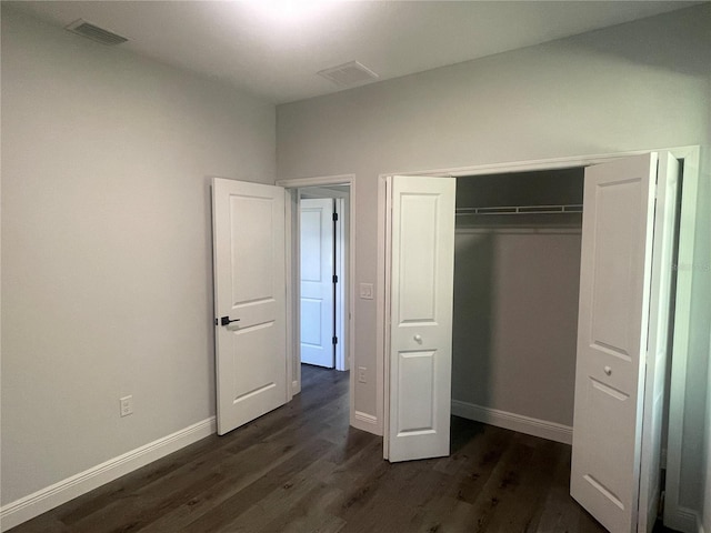 unfurnished bedroom with dark wood-type flooring and a closet