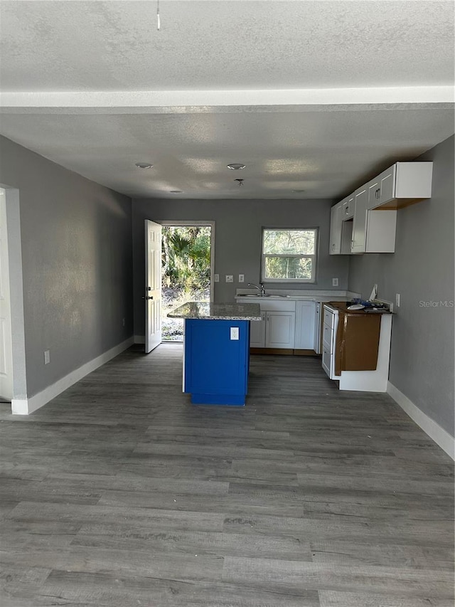 kitchen with a center island, a textured ceiling, white cabinets, and dark hardwood / wood-style floors