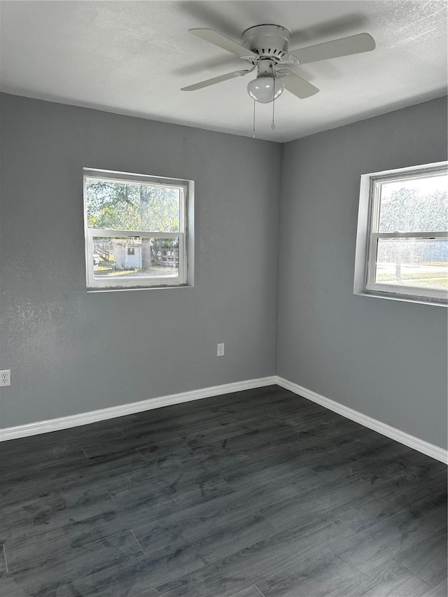 unfurnished room with a wealth of natural light, dark hardwood / wood-style floors, and ceiling fan